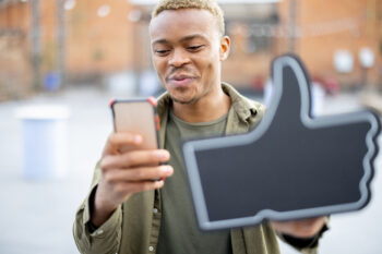 man holding like button while on his smartphone and social media 