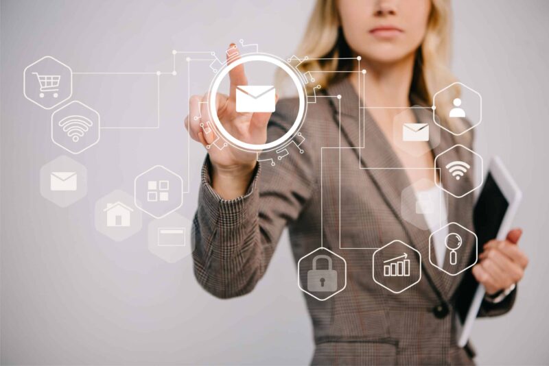 cropped view on businesswoman in suit holding digital tablet and pointing at email marketing icons What is Email Automation?