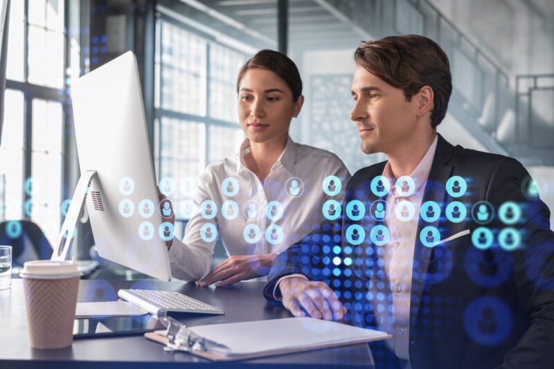 Businessman and businesswoman in formal wear working together looking for new employees to hire for international business consulting. HR, social media icons over modern panoramic office background HR using artificial intelligence tools for recruitment