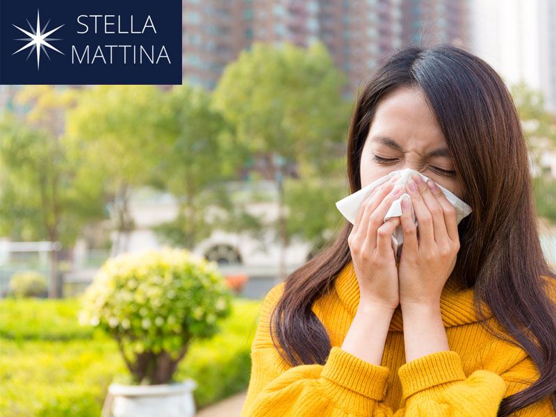 Young woman in a park sneezing to illustrate allergy season