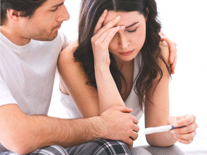 Upset woman with negative pregnancy test to illustrate signs of infertility